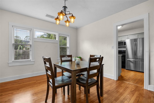 dining space with a chandelier and light hardwood / wood-style flooring