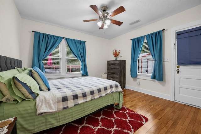 bedroom featuring multiple windows, hardwood / wood-style flooring, and ceiling fan