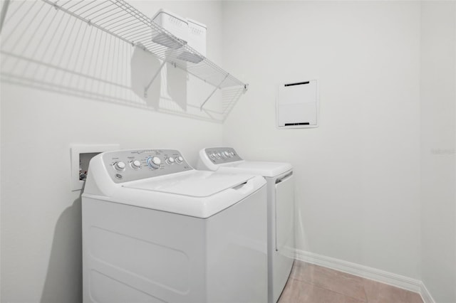 washroom with washing machine and clothes dryer and light tile patterned flooring