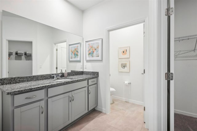 bathroom with toilet, vanity, and tile patterned floors