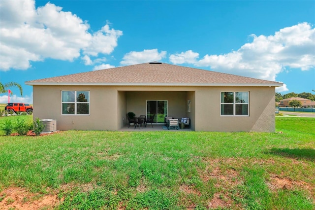 rear view of property with central air condition unit, a lawn, and a patio area