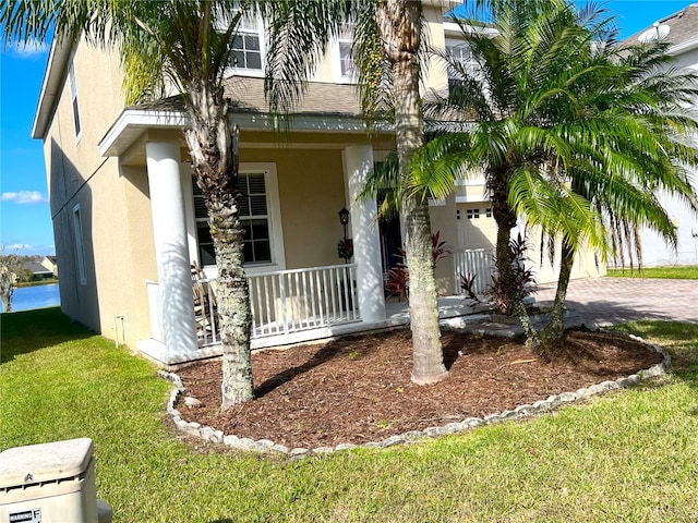 view of front of property featuring a garage, a porch, and a front lawn