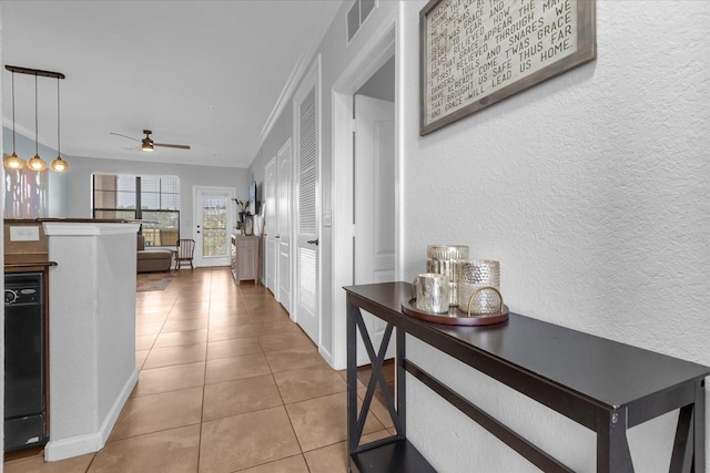 hallway with light tile patterned floors and crown molding