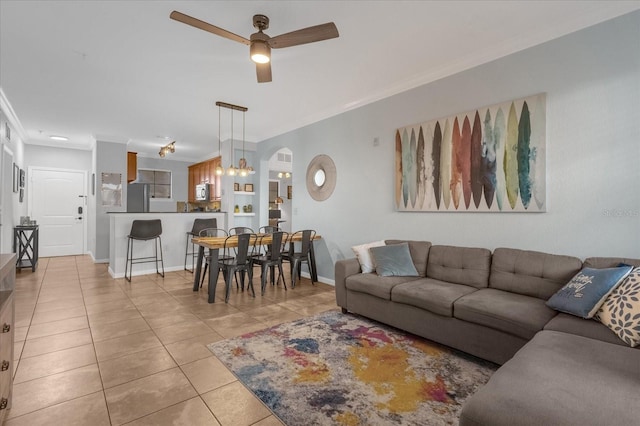 living room with light tile patterned floors, ceiling fan, and crown molding