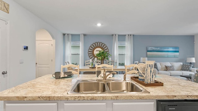 kitchen with white cabinets, a center island with sink, and sink