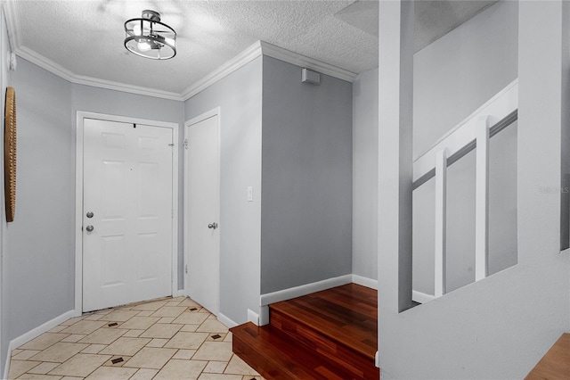 foyer entrance featuring a textured ceiling, ornamental molding, and light hardwood / wood-style flooring