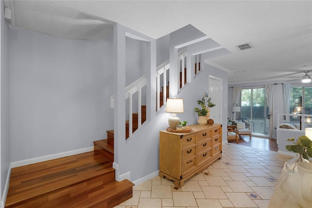 staircase with hardwood / wood-style flooring, ceiling fan, and a textured ceiling