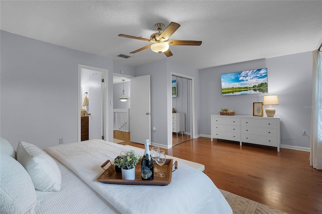 bedroom with ceiling fan, a textured ceiling, and dark hardwood / wood-style floors