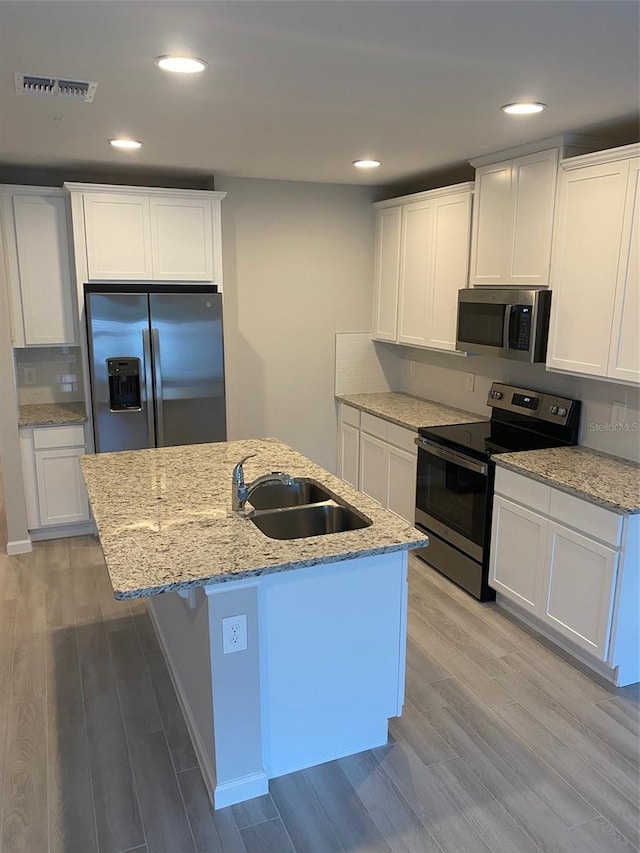 kitchen featuring sink, light hardwood / wood-style flooring, a kitchen island with sink, white cabinets, and appliances with stainless steel finishes