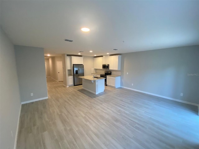 kitchen with sink, light hardwood / wood-style flooring, a kitchen island, white cabinetry, and stainless steel appliances