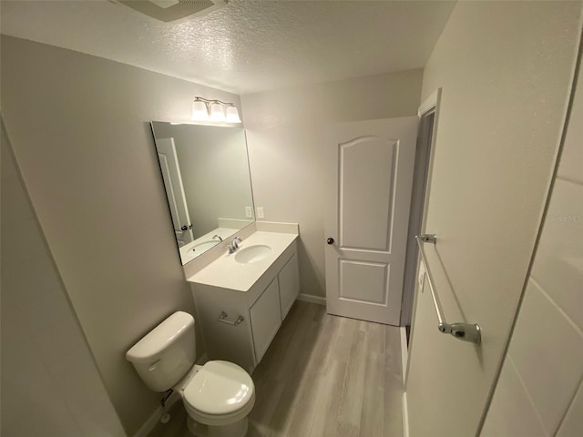 bathroom with hardwood / wood-style flooring, vanity, toilet, and a textured ceiling