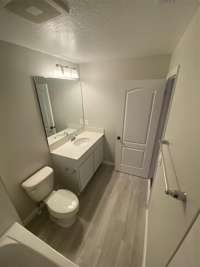 bathroom featuring hardwood / wood-style floors, vanity, a textured ceiling, and toilet