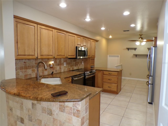 kitchen featuring dark stone counters, kitchen peninsula, sink, and stainless steel appliances