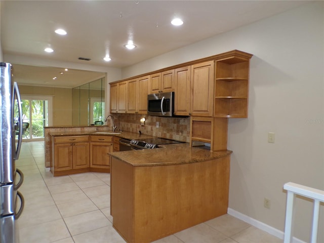 kitchen with kitchen peninsula, stainless steel appliances, dark stone counters, and sink