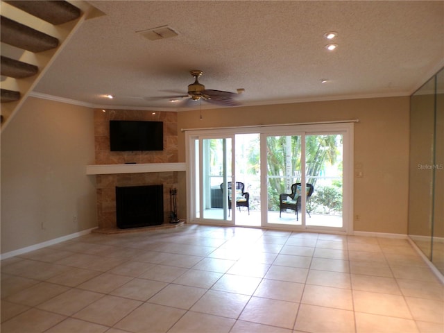 unfurnished living room with ornamental molding, light tile patterned flooring, a textured ceiling, a tiled fireplace, and ceiling fan