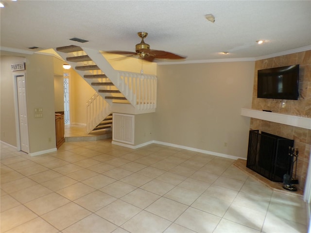 unfurnished living room featuring light tile patterned flooring, a tiled fireplace, ceiling fan, and crown molding