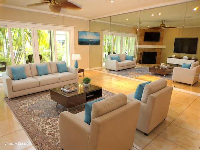 tiled living room featuring ceiling fan, a large fireplace, and crown molding