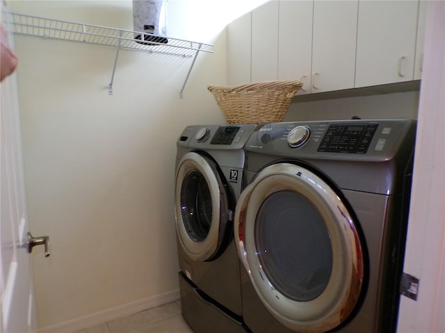 laundry area with cabinets, washing machine and dryer, and light tile patterned floors