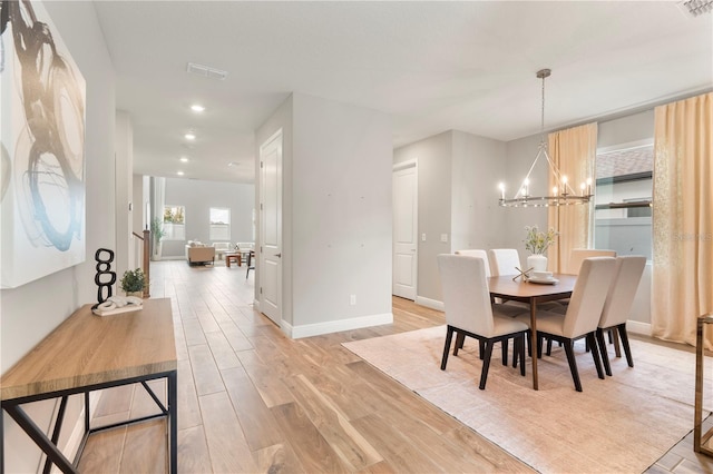 dining space featuring light hardwood / wood-style flooring and an inviting chandelier