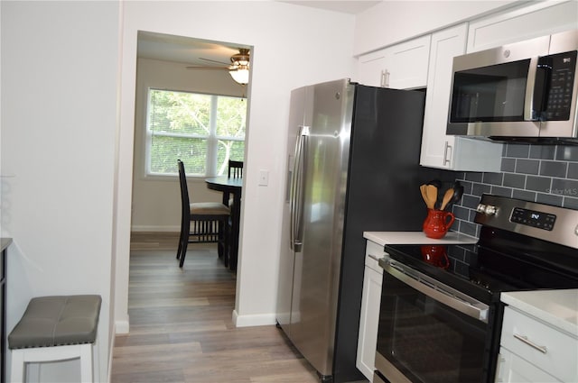 kitchen with stainless steel appliances, decorative backsplash, white cabinets, ceiling fan, and light hardwood / wood-style flooring