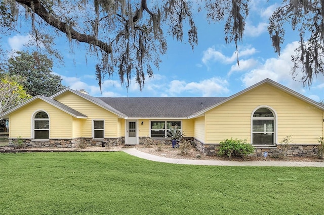 ranch-style house with stone siding, a front yard, and roof with shingles