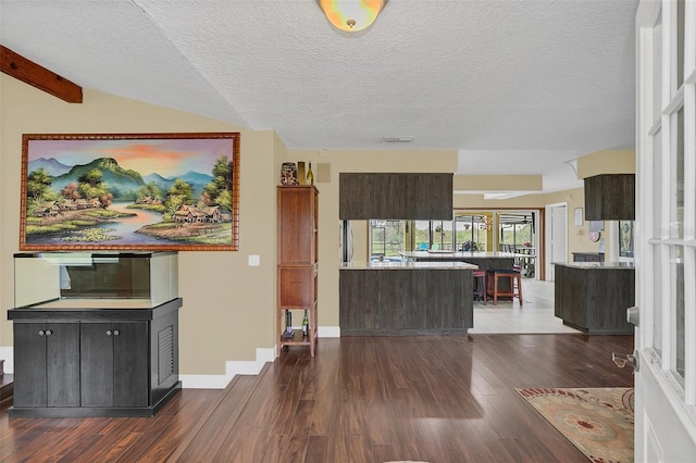 living area with dark wood-type flooring, a textured ceiling, and baseboards