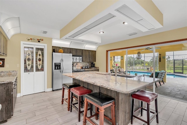 kitchen featuring stainless steel appliances, a breakfast bar area, a sink, and dark brown cabinets