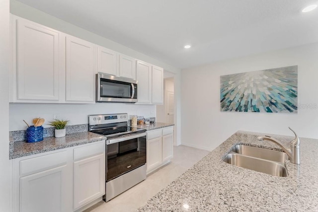 kitchen featuring white cabinetry, sink, light stone countertops, and appliances with stainless steel finishes