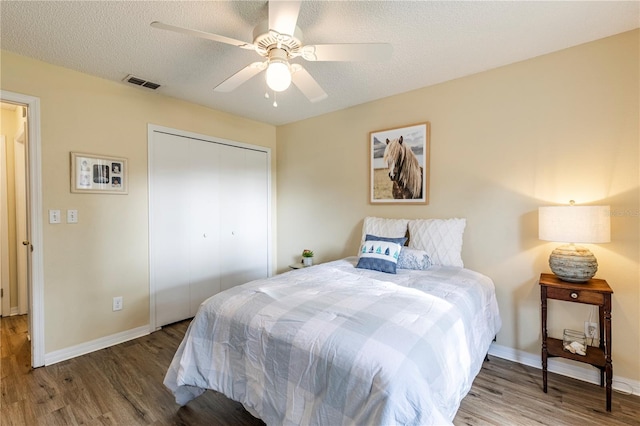 bedroom with a closet, ceiling fan, dark wood-type flooring, and a textured ceiling