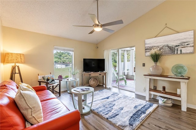 living room with hardwood / wood-style flooring, a textured ceiling, lofted ceiling, and ceiling fan