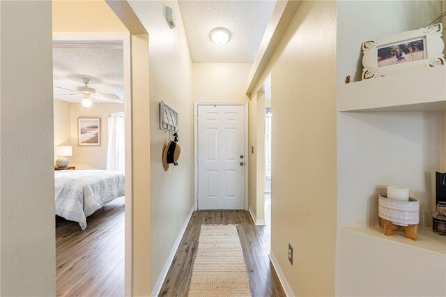 hallway with a textured ceiling and hardwood / wood-style floors