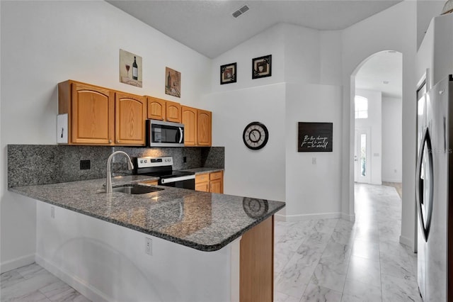 kitchen with stainless steel appliances, dark stone countertops, kitchen peninsula, and high vaulted ceiling