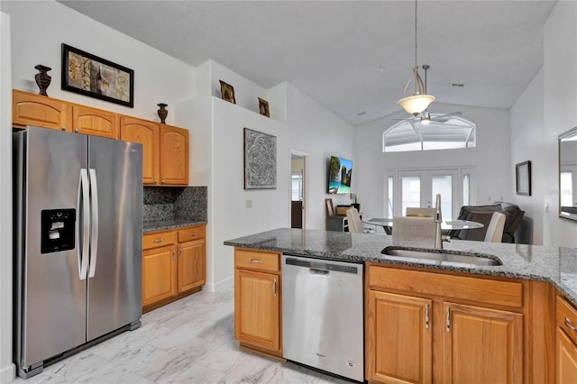 kitchen with stainless steel appliances, sink, dark stone counters, ceiling fan, and vaulted ceiling