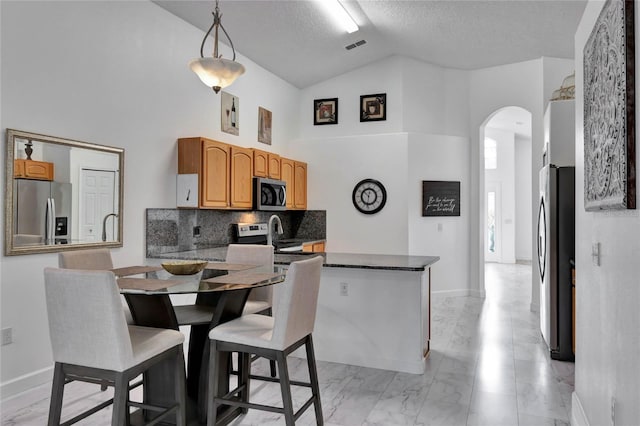 kitchen featuring hanging light fixtures, kitchen peninsula, a textured ceiling, and stainless steel appliances