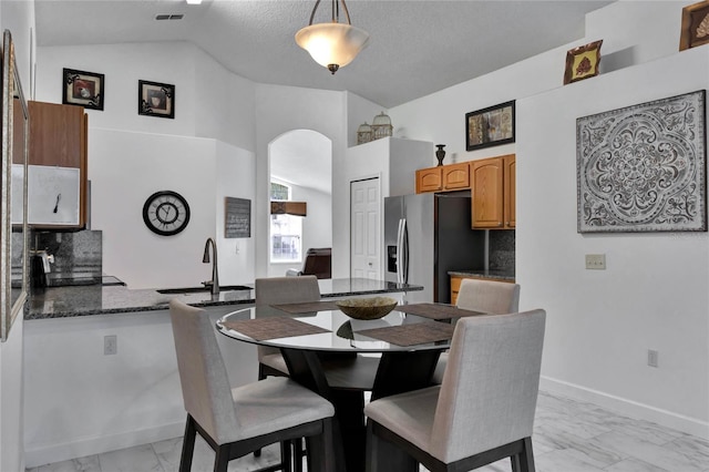 dining area featuring a textured ceiling, sink, and high vaulted ceiling