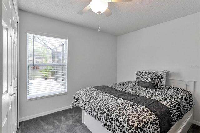 carpeted bedroom with a closet, multiple windows, a textured ceiling, and ceiling fan