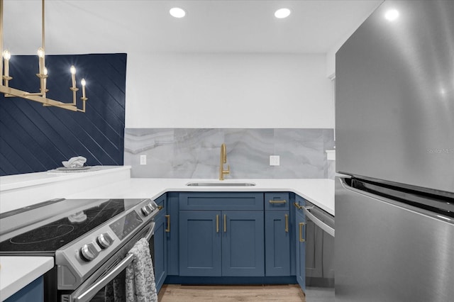 kitchen with sink, hanging light fixtures, light hardwood / wood-style flooring, a chandelier, and appliances with stainless steel finishes