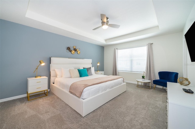 bedroom featuring ceiling fan, light carpet, and a tray ceiling