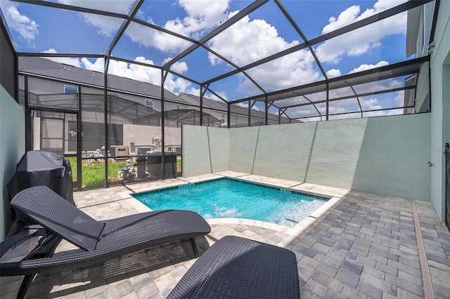 view of swimming pool featuring glass enclosure and a patio