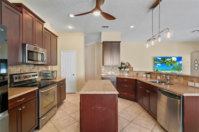 kitchen featuring stainless steel appliances, sink, decorative light fixtures, a kitchen island, and decorative backsplash