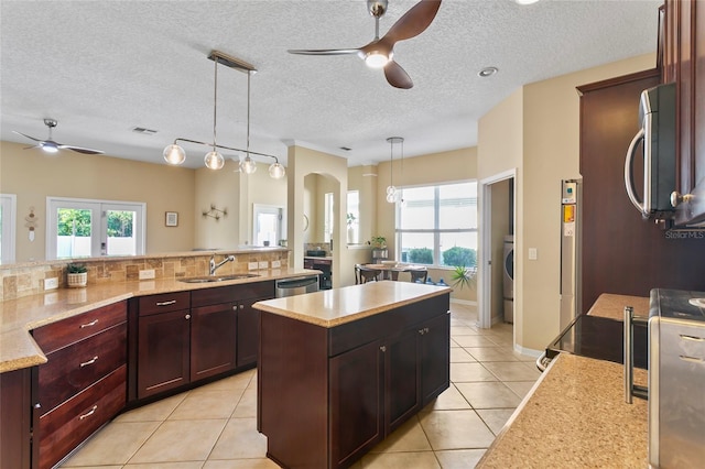 kitchen featuring stainless steel appliances, decorative backsplash, sink, a kitchen island, and decorative light fixtures