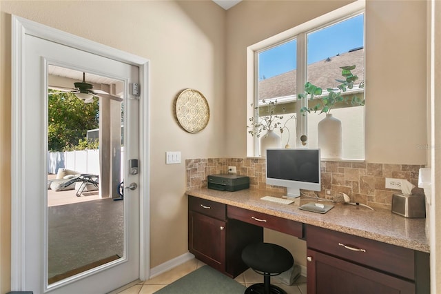 office space featuring light tile patterned flooring, built in desk, ceiling fan, and a wealth of natural light