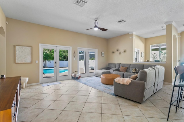 tiled living room with a wealth of natural light, a textured ceiling, and french doors