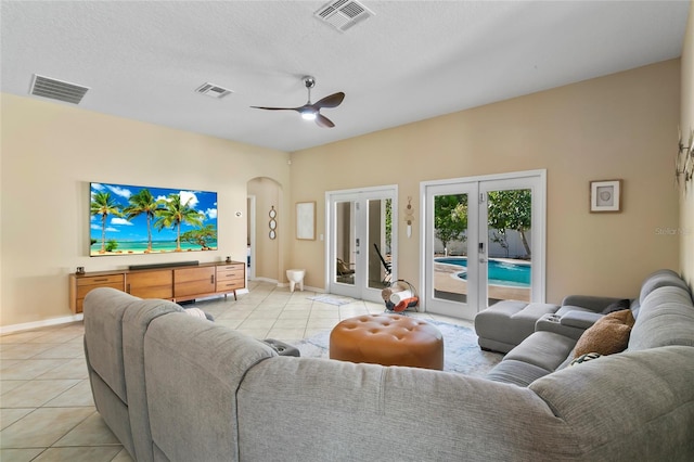 tiled living room with ceiling fan, a textured ceiling, and french doors