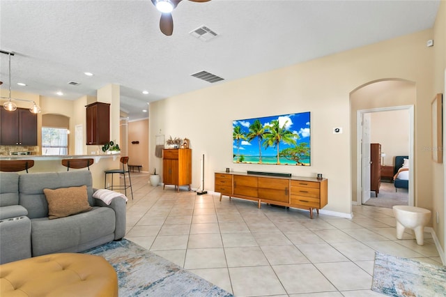 tiled living room with a textured ceiling and ceiling fan