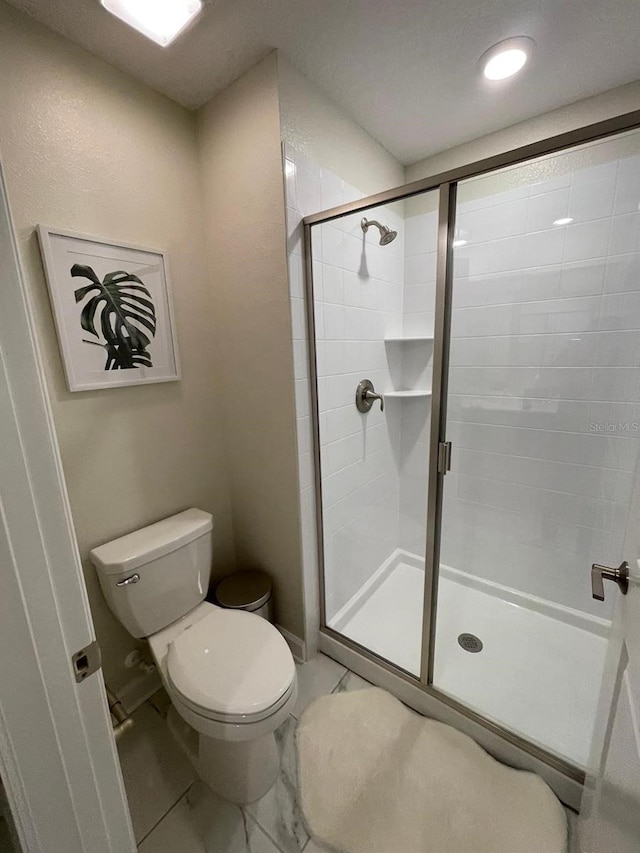 bathroom with toilet and a shower with shower door