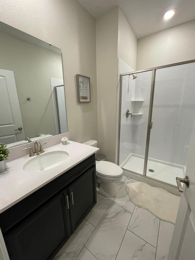 bathroom featuring vanity, toilet, and a shower with door