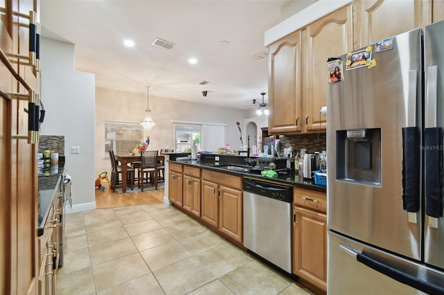 kitchen with stainless steel appliances, hanging light fixtures, light tile patterned floors, ceiling fan, and dark stone countertops