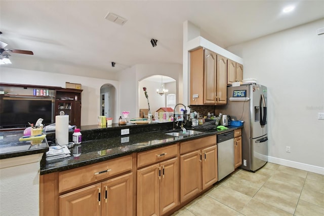 kitchen with stainless steel appliances, light tile patterned flooring, sink, dark stone countertops, and ceiling fan