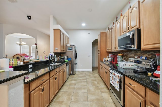 kitchen featuring light tile patterned flooring, sink, appliances with stainless steel finishes, dark stone countertops, and a notable chandelier